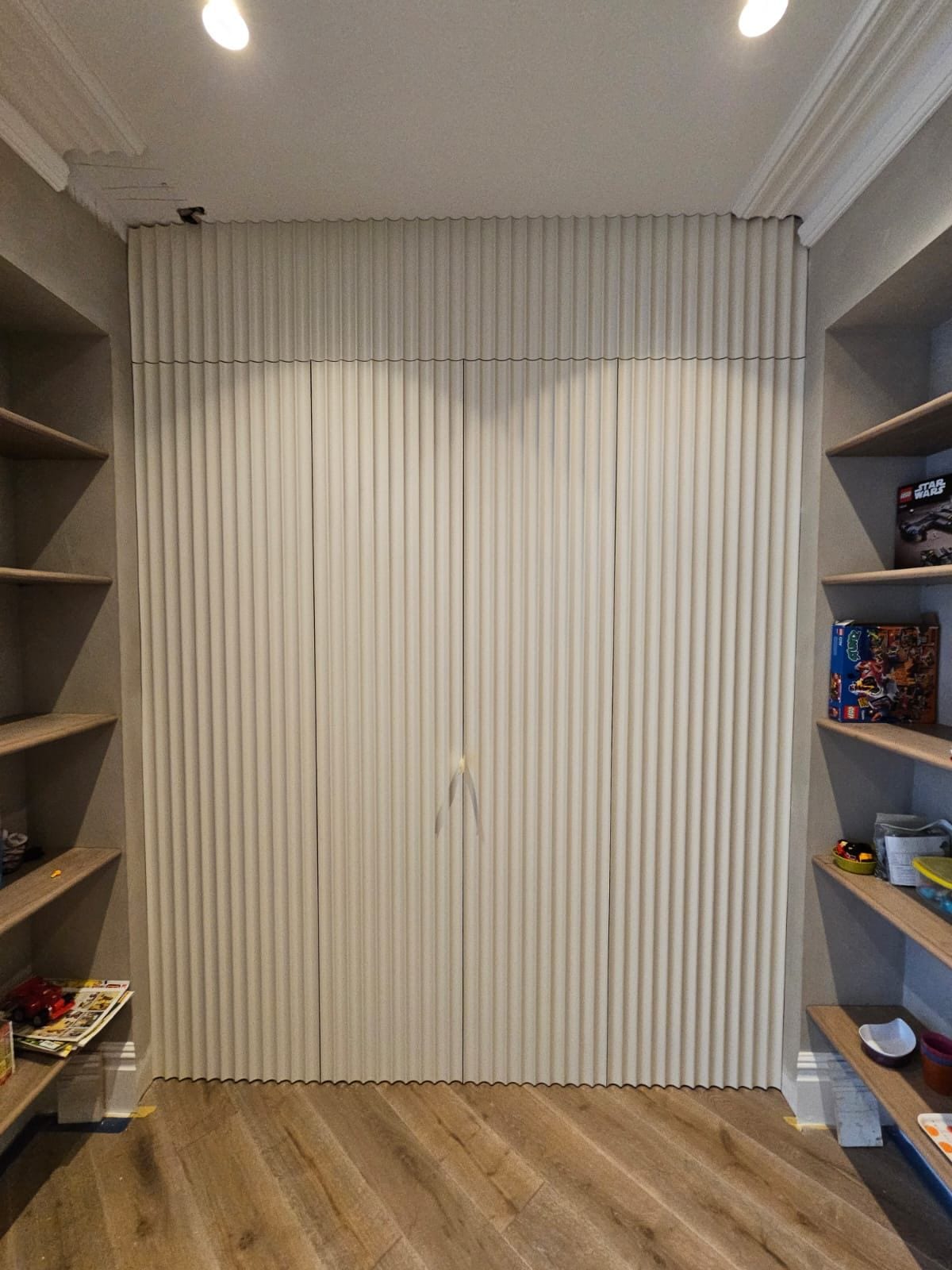 Floor-to-ceiling fluted wall concealing bespoke fitted storage