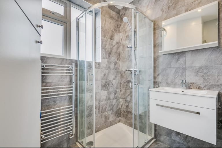 Finished grey tiled shower room with glass enclosure and wall-hung vanity