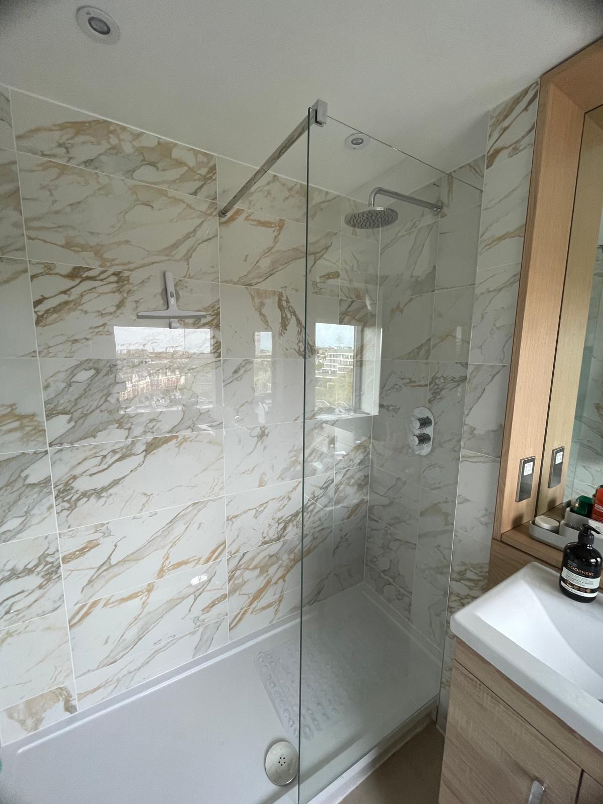 Marble-effect walk-in shower renovation with frameless glass screen and rainfall shower